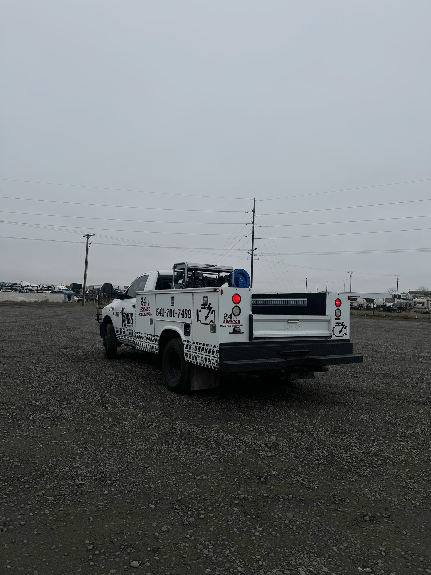 A white truck is parked in a gravel lot.
