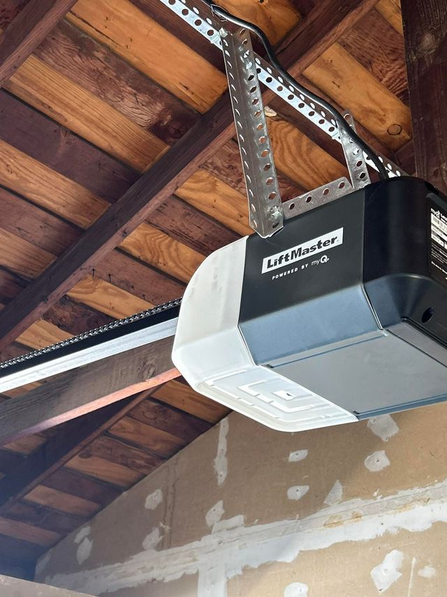 Garage door opener mounted to a wooden ceiling above a partially finished wall