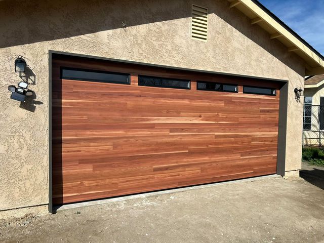 Closed wood-paneled garage door on a beige house exterior under daylight