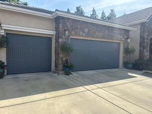 Two-car garage with stone facade and dark doors in a residential driveway