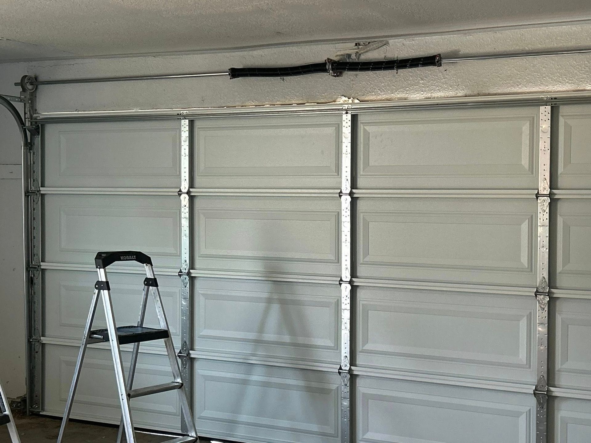 Garage interior with a white paneled door and a step ladder in front of it