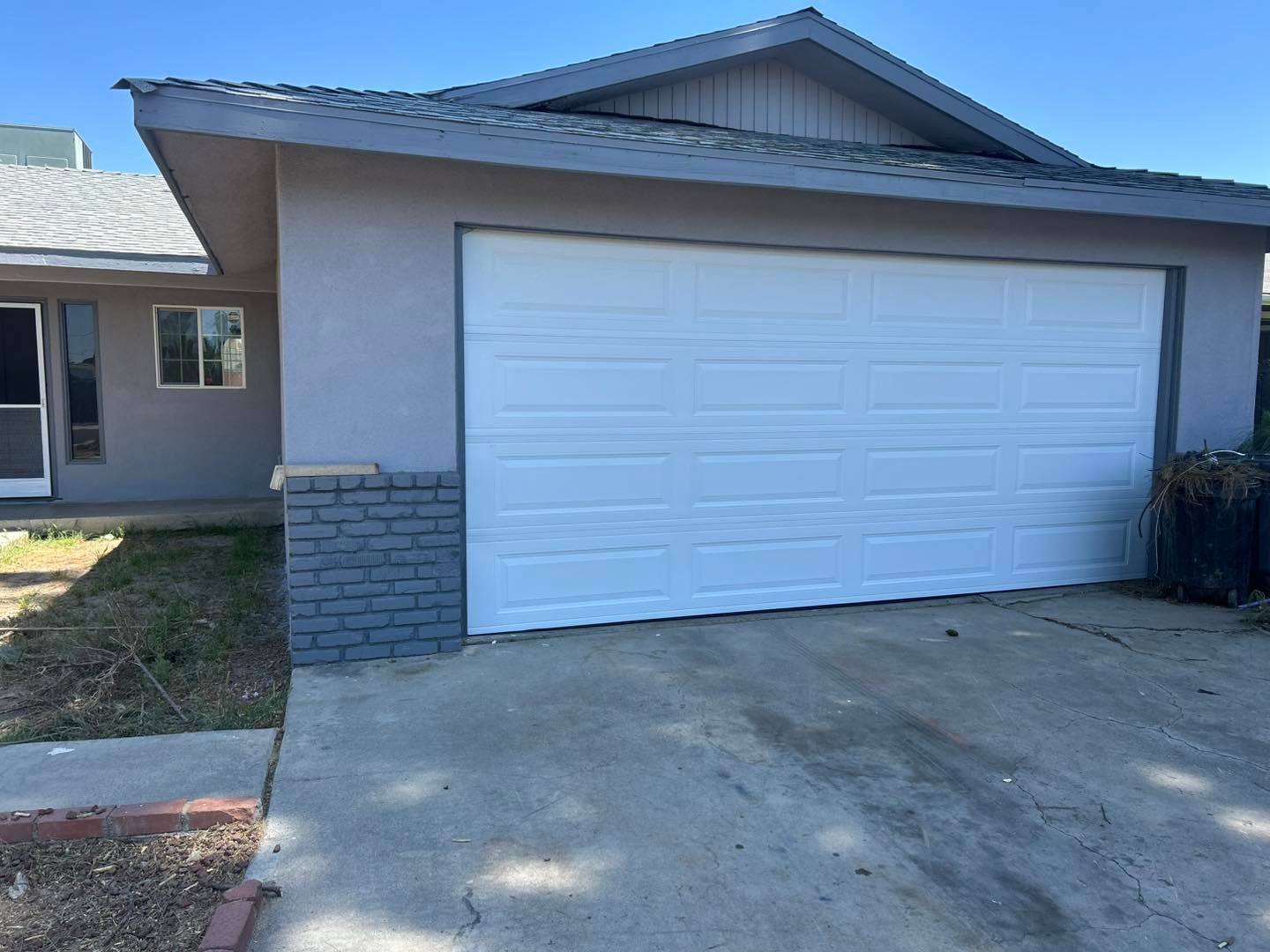 Suburban house exterior with a white garage door and concrete driveway
