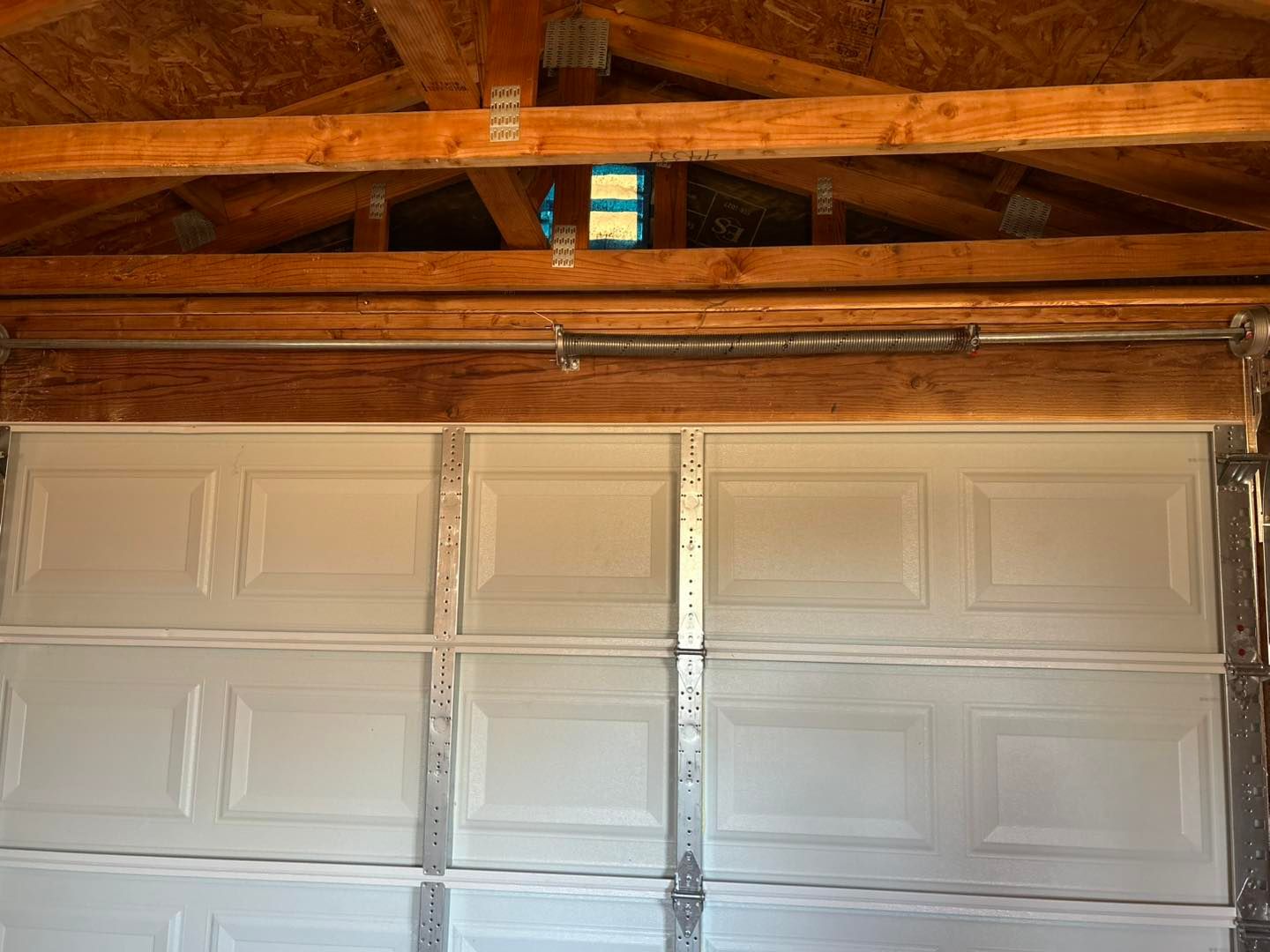 White garage door beneath exposed wooden rafters and ceiling beams