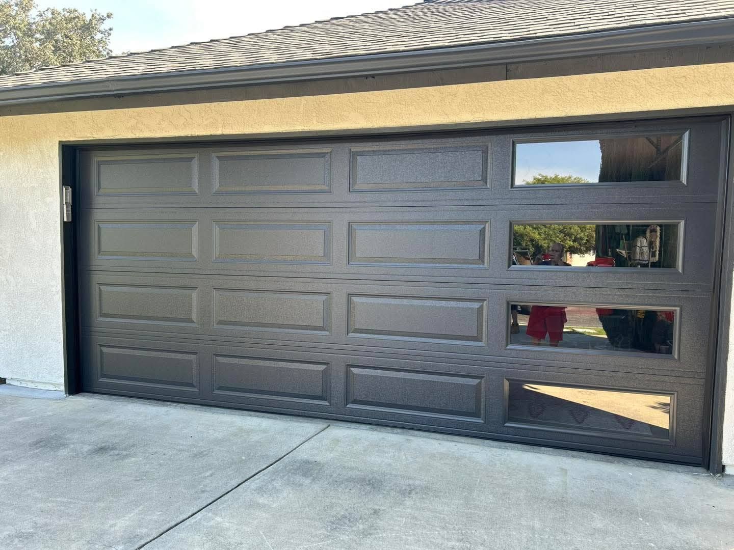 Black garage door with three narrow windows on the right side of a house.