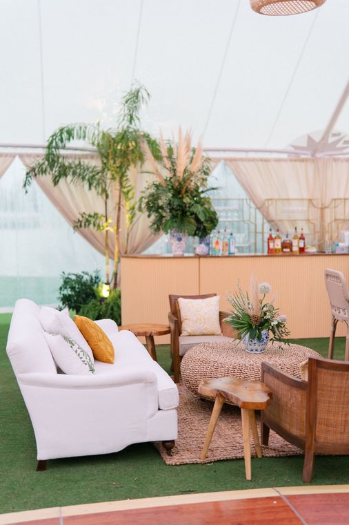 A white couch and a glass table are under a tent.