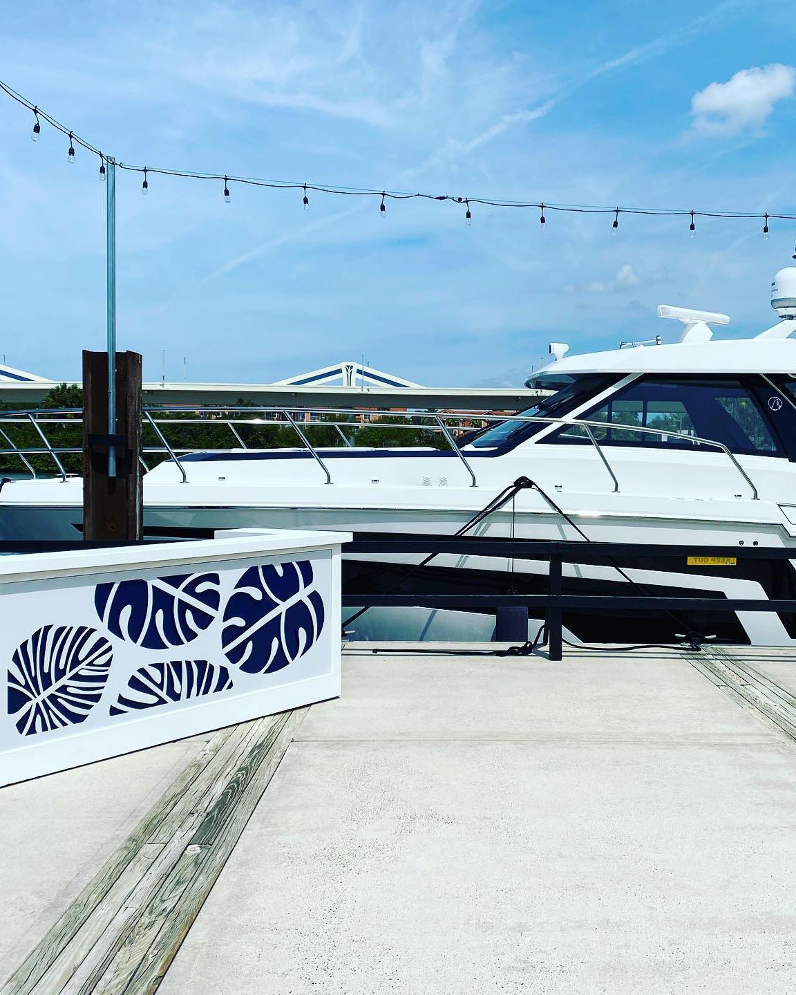 A white boat is docked next to a sign with blue leaves on it