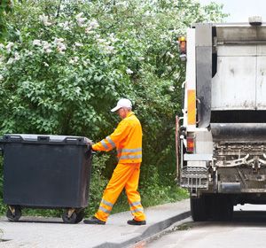 Old man pulling a trash container