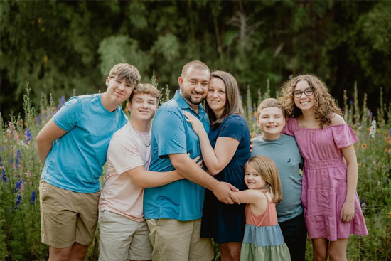 A happy family is posing for a picture in a field of flowers.