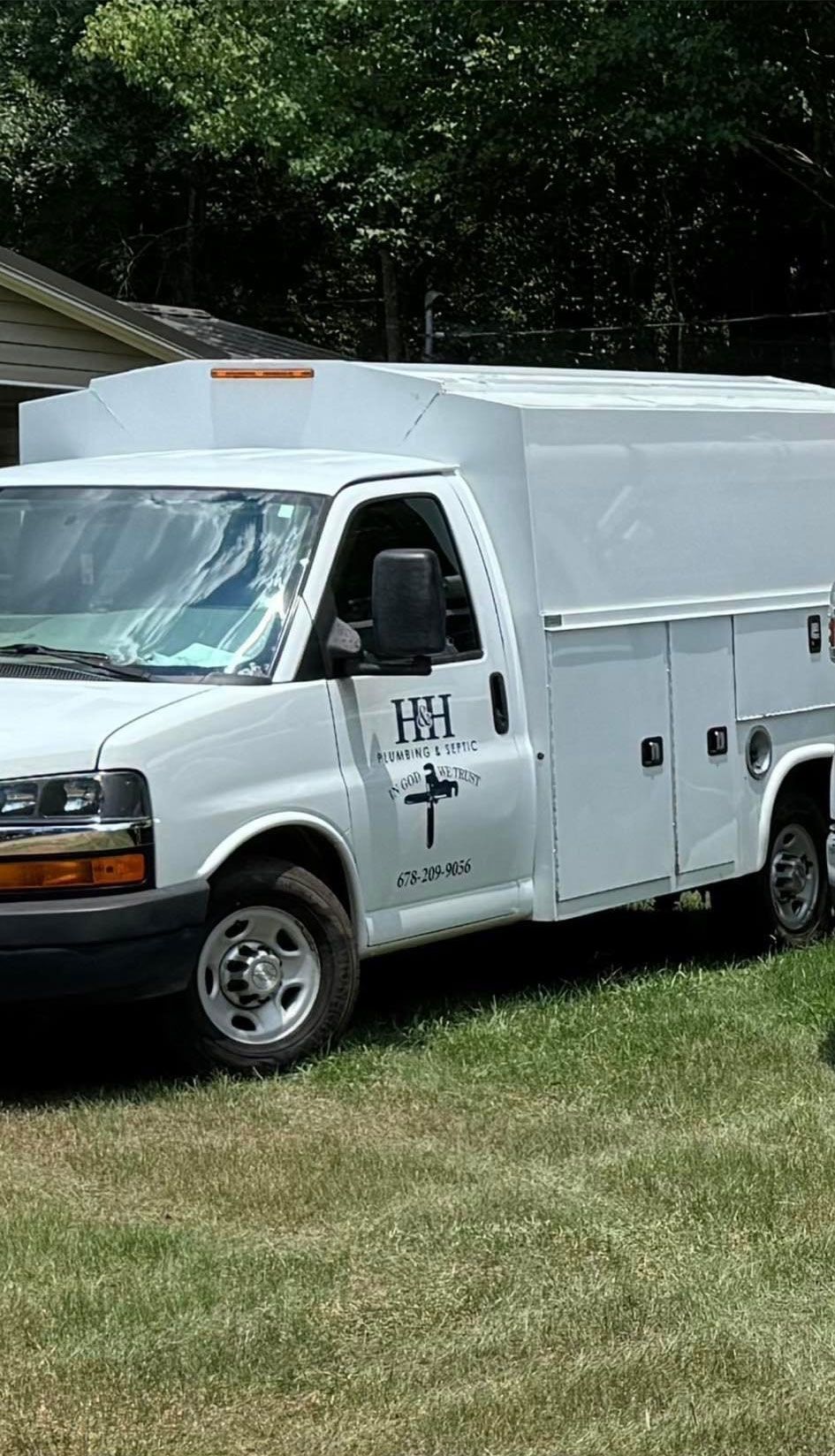 A white van with a cross on the side is parked in a grassy field