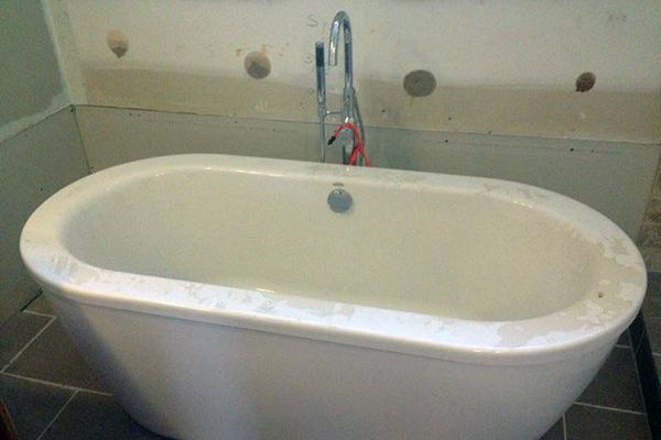 A white bathtub is sitting on a tiled floor in a bathroom.