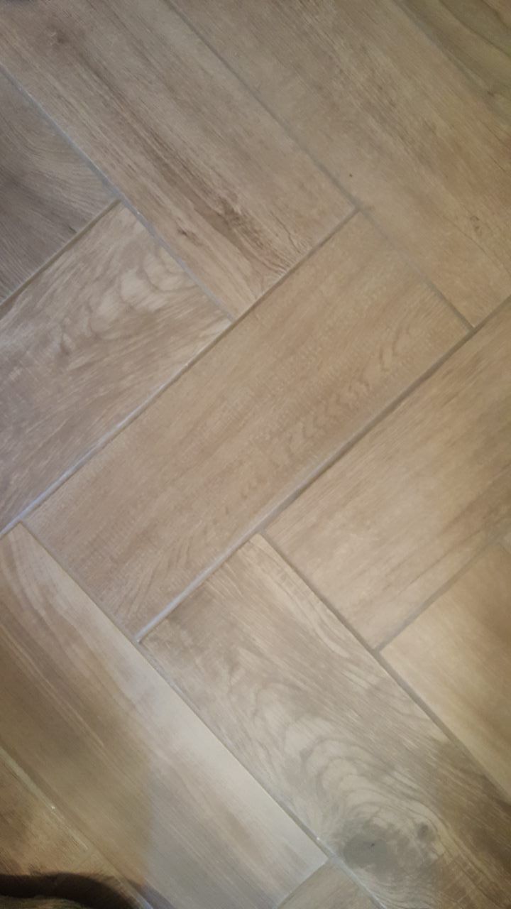 Herringbone pattern wooden floor tiles. The tiles are light brown with wood grain detail.
