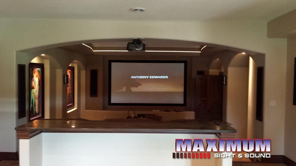 Home theater with projector, screen, bar, and speakers.
