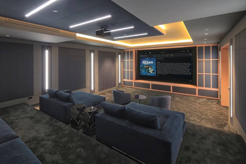 Home theater with blue couches, large screen, and modern lighting.