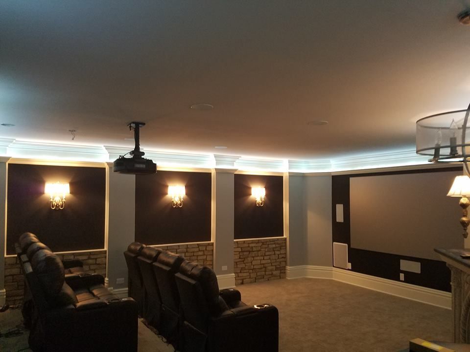 Home theater with recliner seating, screen, projector, decorative lighting, and stone wall accents.