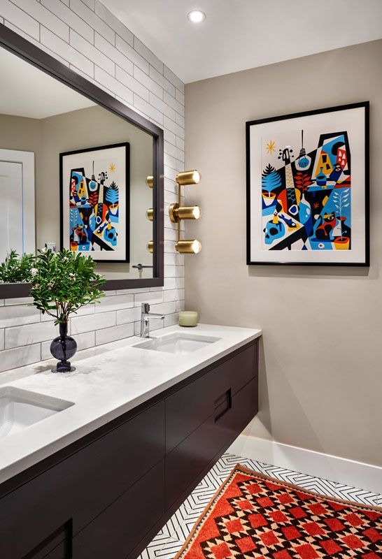 Modern bathroom: dark vanity, white countertops, two sinks, artwork, and a red patterned rug.