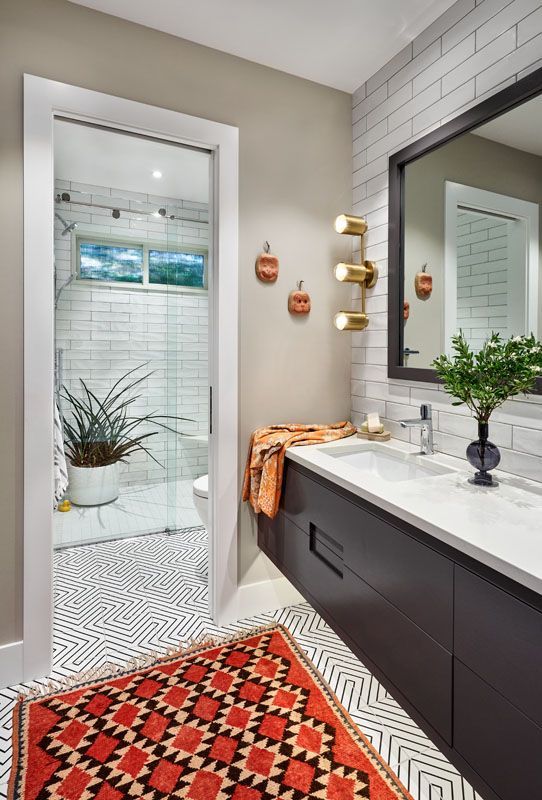 Bathroom with dark vanity, red rug, patterned floor, and white brick shower.