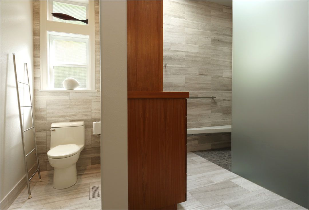 Bathroom interior with wood cabinets, toilet, and frosted glass shower door.