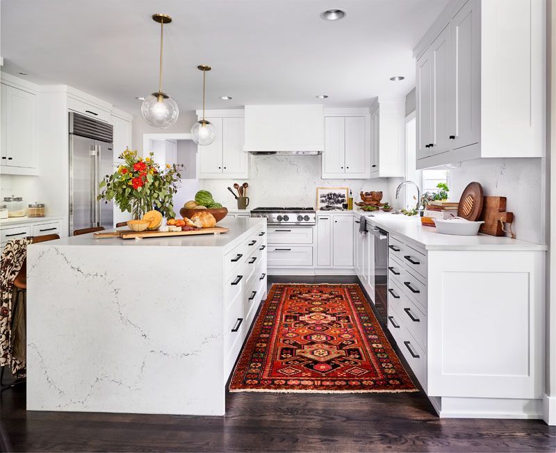White kitchen with island and cabinetry, rug, and dark wood floor.