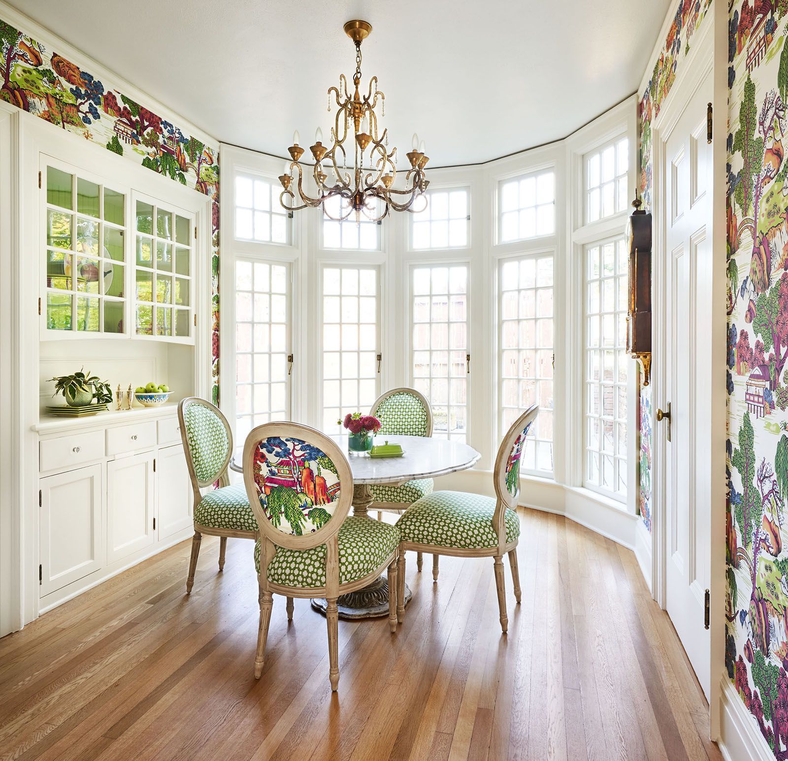 Dining room with a round table, chairs, built-in cabinet, and floral wallpaper.
