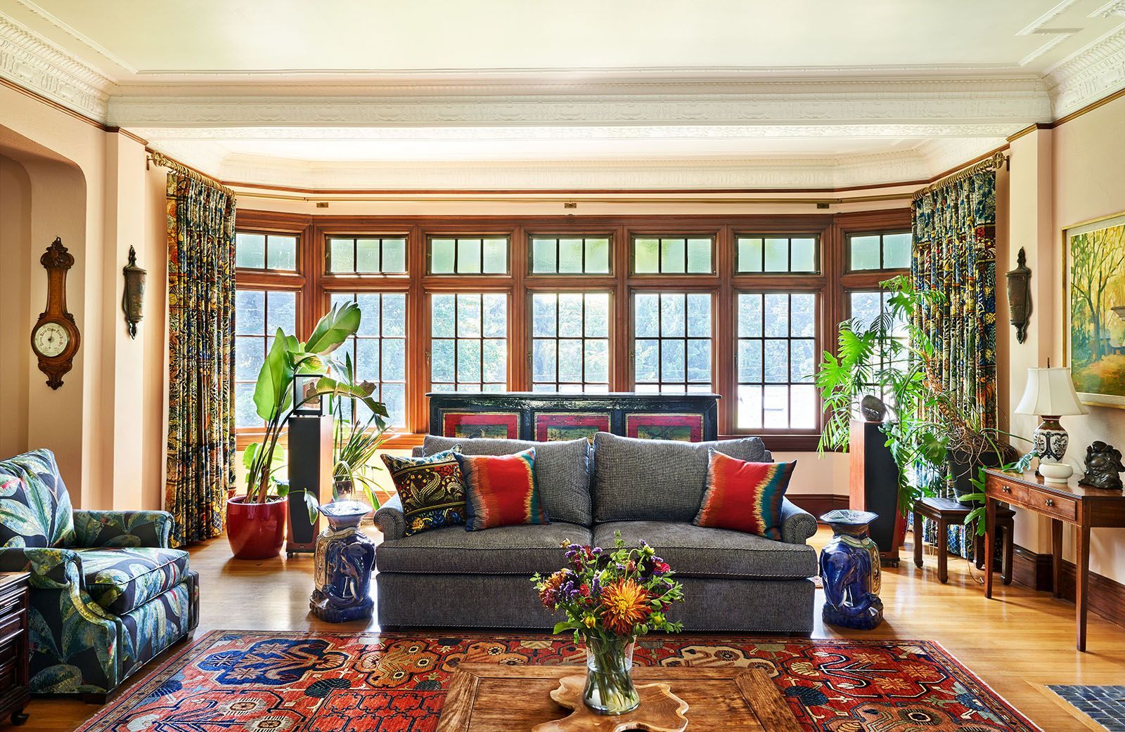 Living room with bay window, floral patterned curtains, sofa, and antique furniture