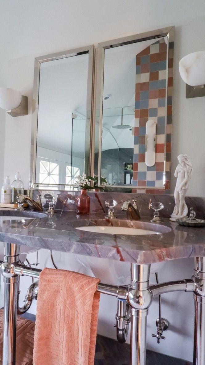 Bathroom with purple marble vanity, two mirrors, chrome fixtures, and a coral towel.