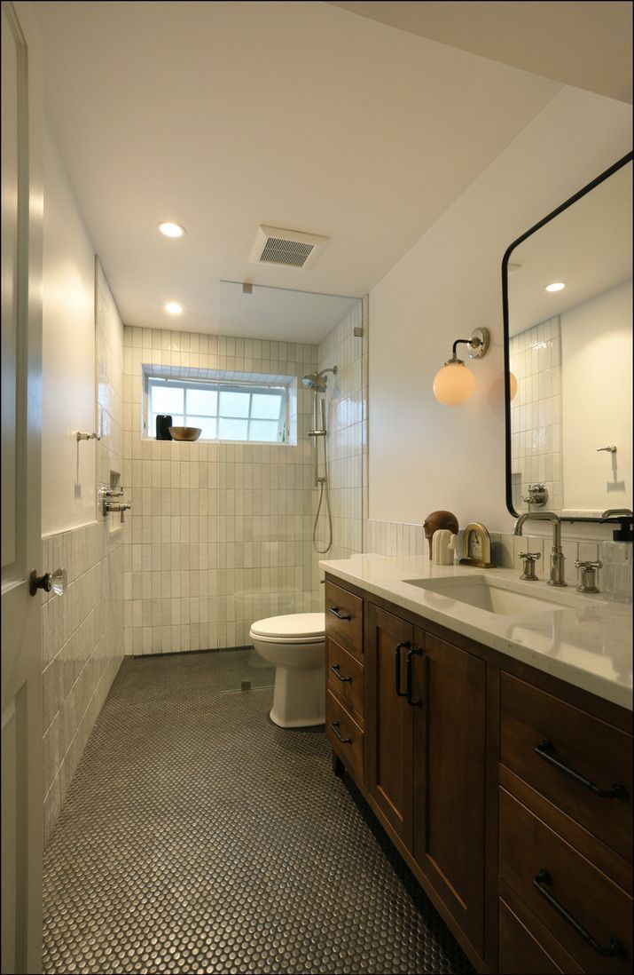 Bathroom with wood vanity, black tile floor, white walls, and a glass shower.