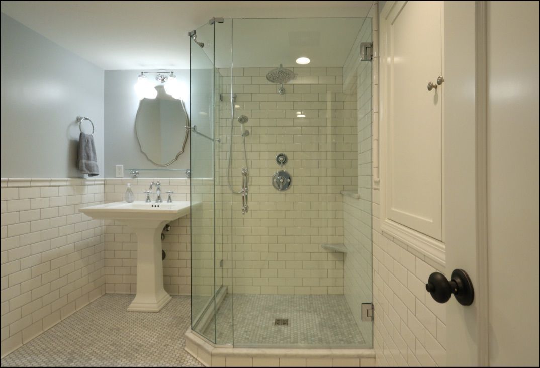 Bathroom with glass shower, pedestal sink, and white tile. Blue wall, gray floor.