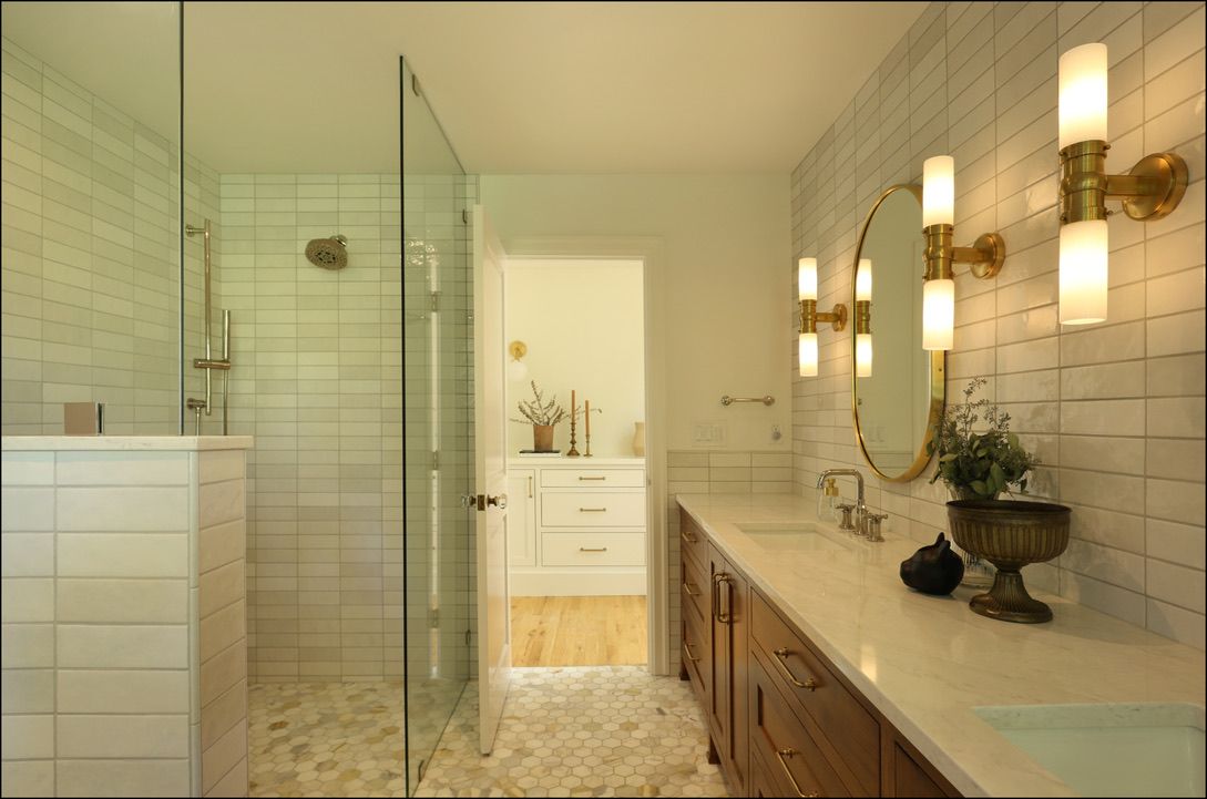 Modern bathroom with a glass shower, long vanity, and gold accents.