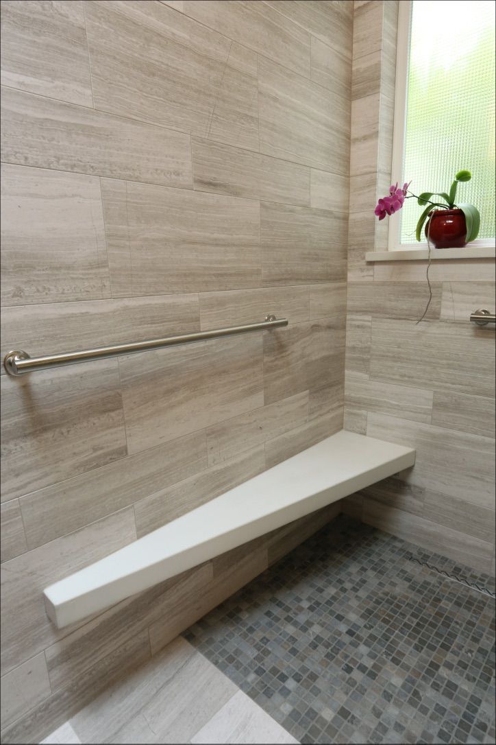 Bathroom with stone tile walls, shower bench, towel bar, and window with plants.