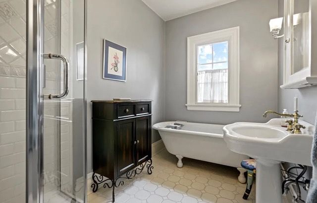 Bathroom with gray walls, a clawfoot tub, and black cabinet.