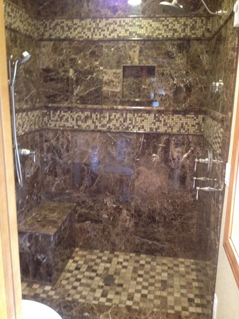 Brown marble shower with mosaic tile accents, a built-in seat, and recessed shelves.
