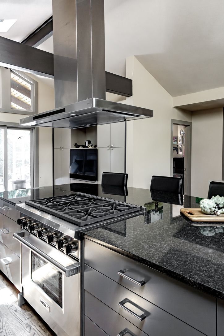 Modern kitchen with stainless steel range and black granite island.
