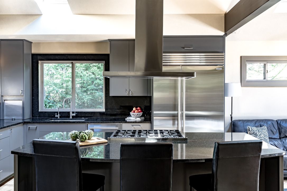 Modern kitchen with a gray island, black countertops, and stainless steel appliances.