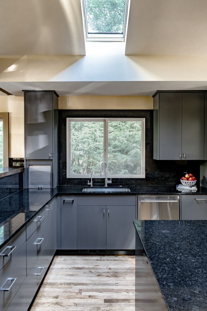 Modern gray kitchen with granite countertops, stainless steel appliances, and a skylight.