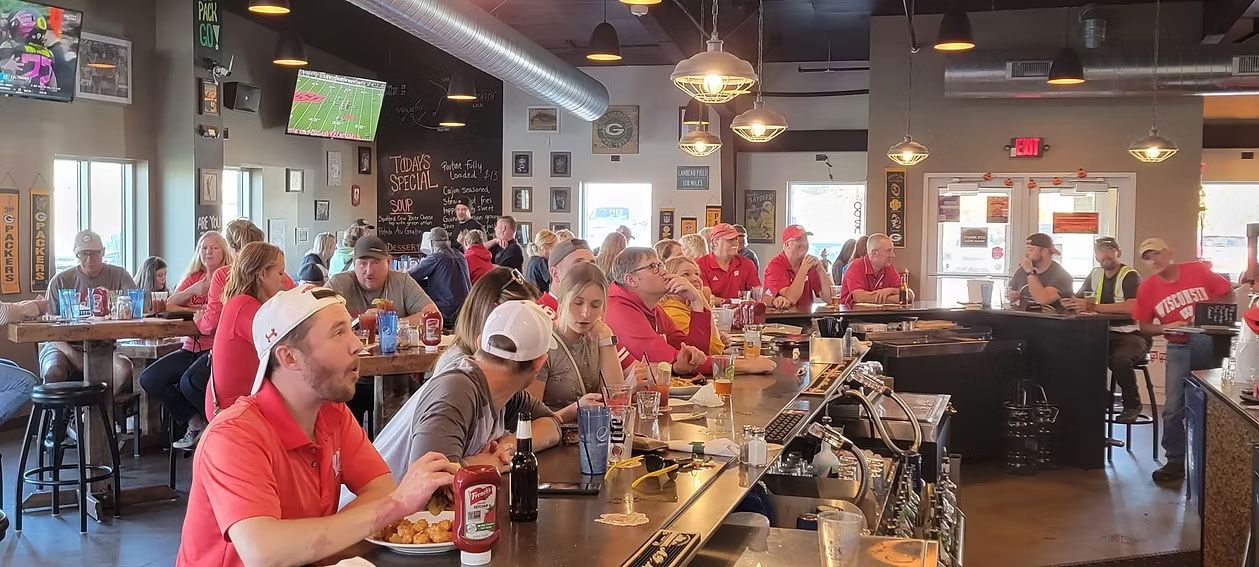 People at a sports bar watching a game, some wearing red shirts.