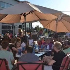 Patio dining: People at tables under large umbrellas, enjoying food and drinks.