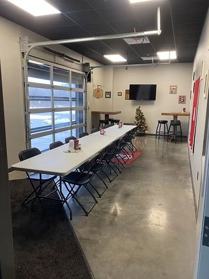 Conference room with long table, chairs, TV, and garage door window.