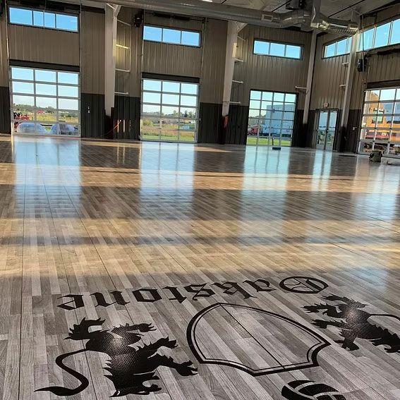 Wooden floor inside a large building with large windows. 
