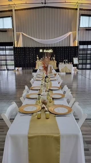 Long banquet table set for a formal event, with gold accents and a decorative backdrop.