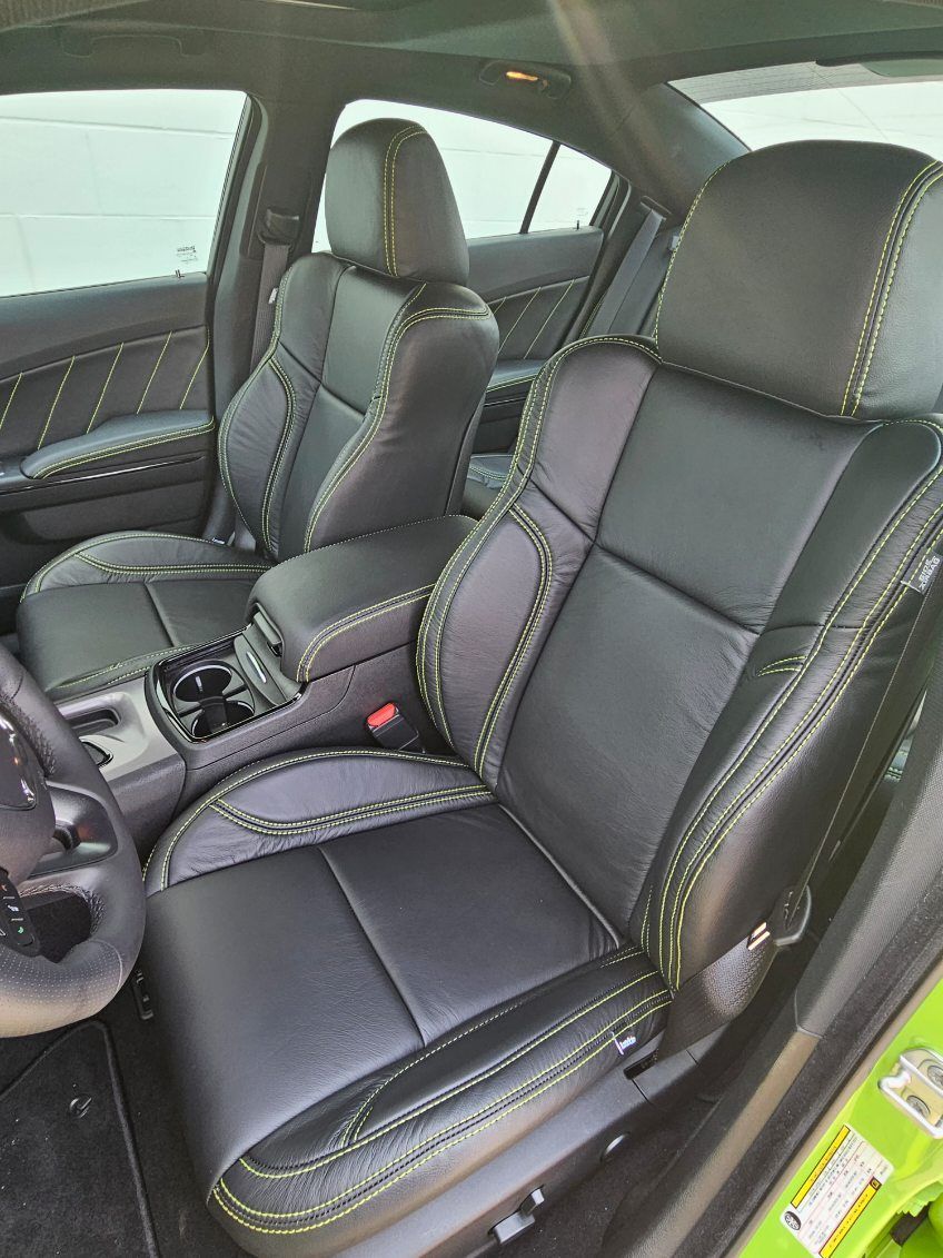 Car interior with black leather bucket seats and yellow stitching, viewed from the front passenger side