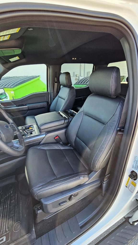 Black leather truck front seats and center console viewed through the open door.