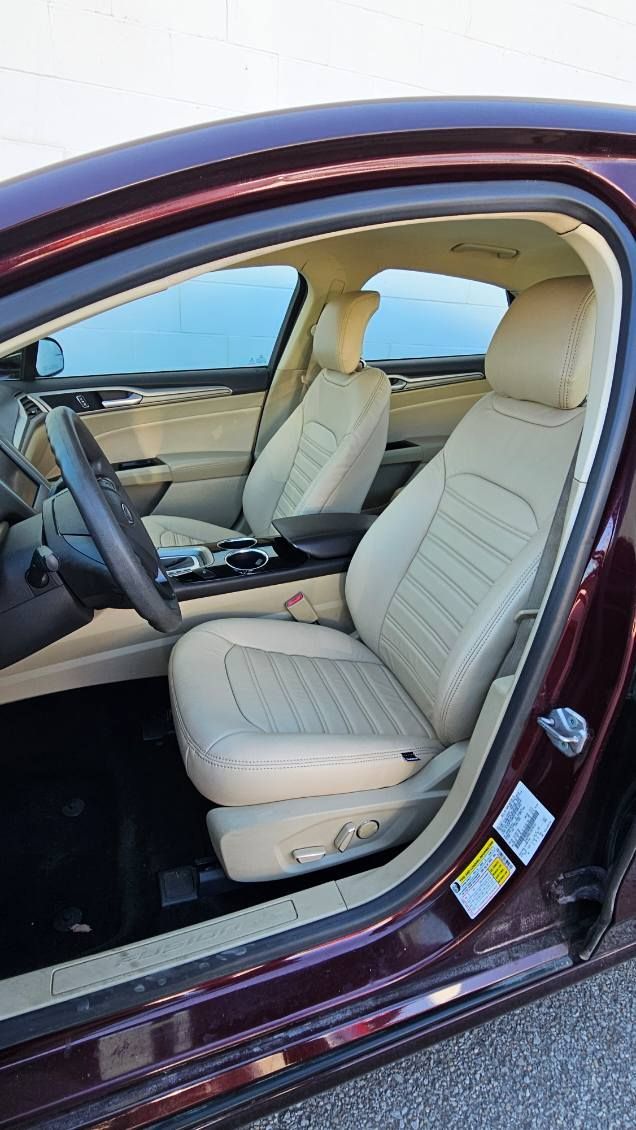 Beige leather car interior with front seats and open driver’s door