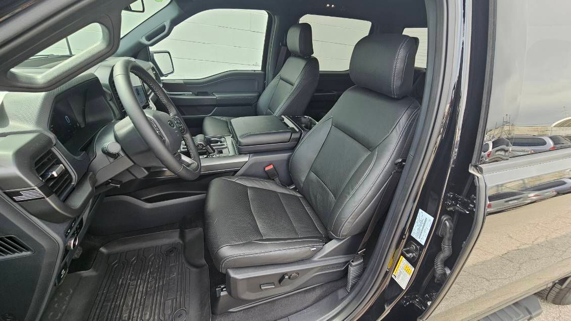Interior of a black SUV, showing the driver and front passenger seats with open door.