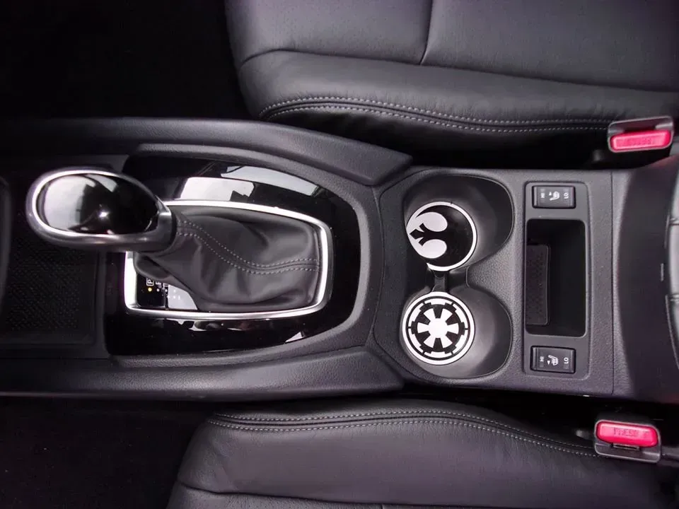 Car center console with gear shift, cup holders, and leather armrest in black interior