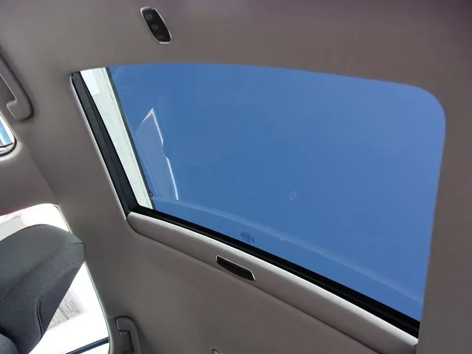View from a car’s interior looking up through a sunroof at a blue sky.
