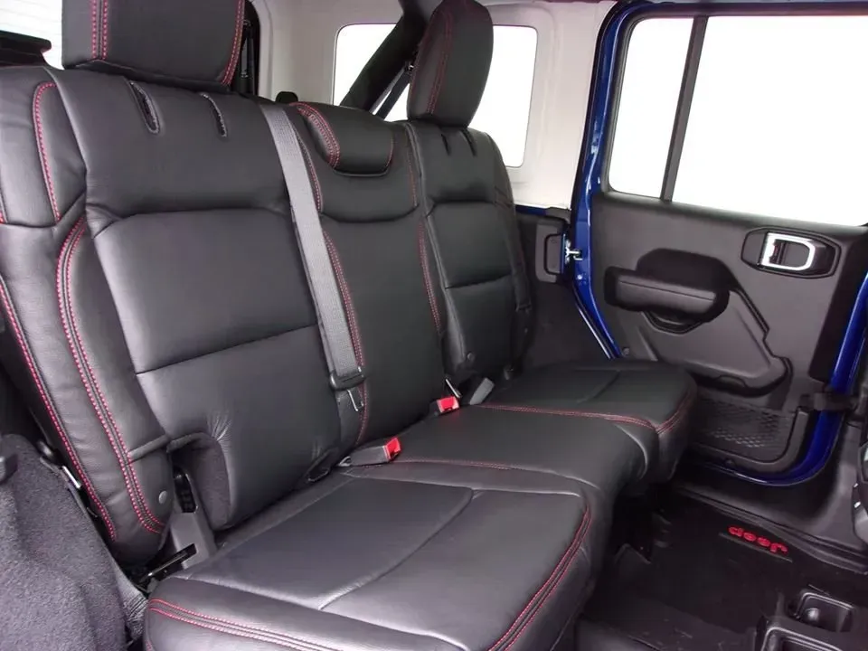 Black leather car back seat with red stitching and blue door trim, viewed from inside the vehicle