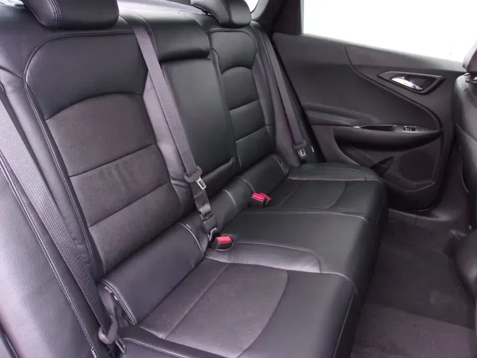 Back seat of a car with black leather seats and seatbelts visible