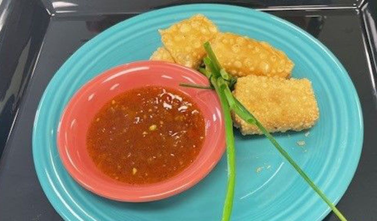 A blue plate topped with fried food and a small bowl of dipping sauce.