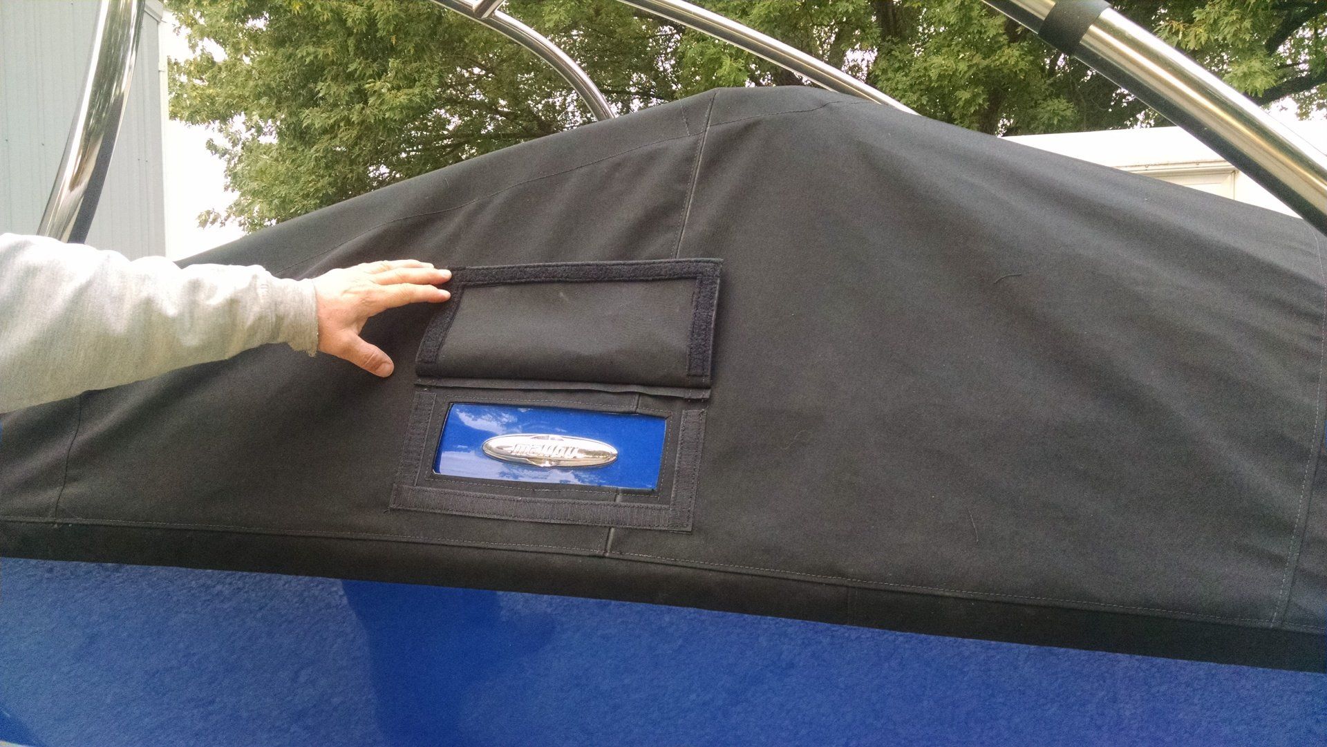 A person is touching a black tent with a blue logo on it