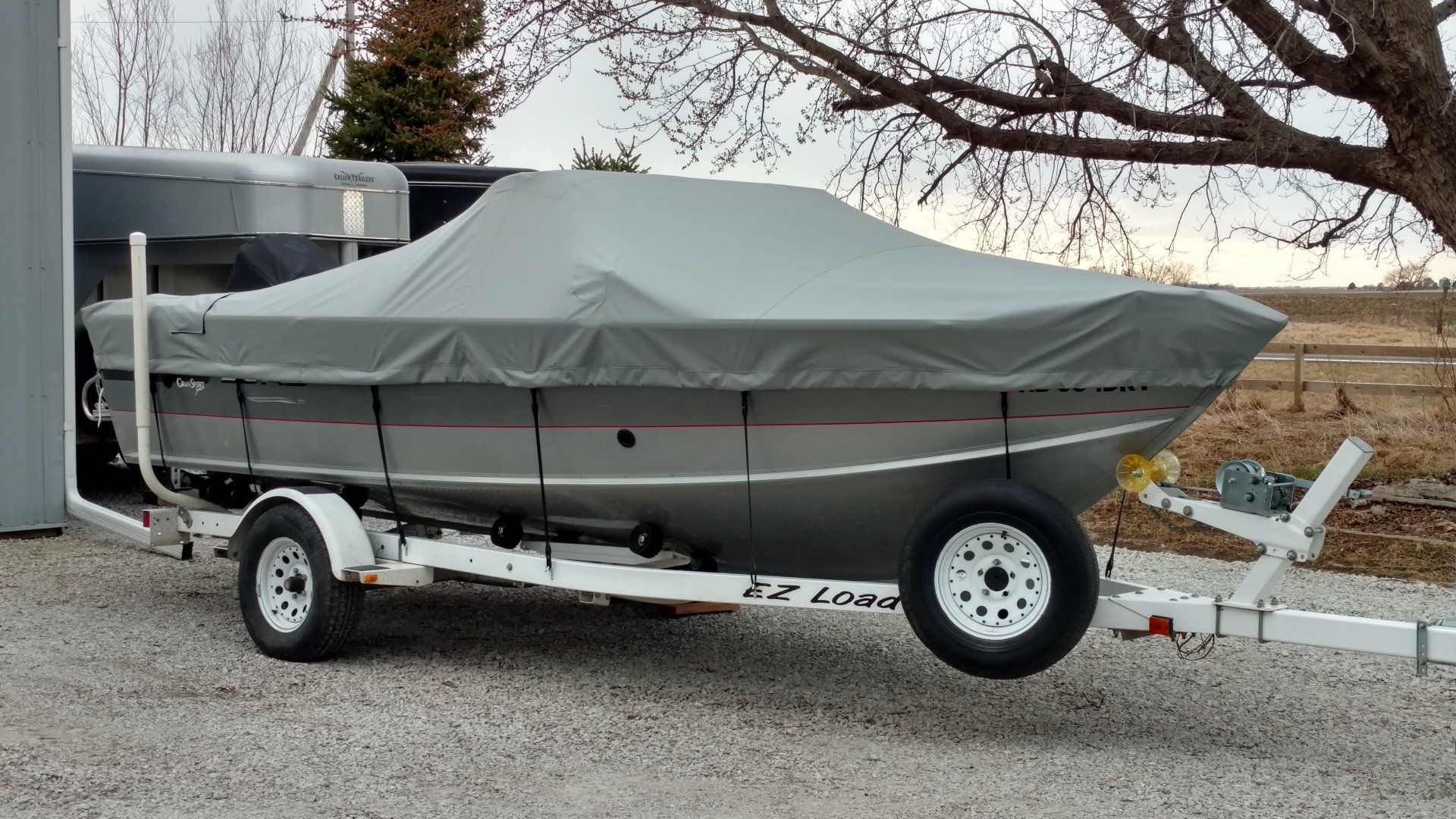 A boat with a cover on it is on a trailer